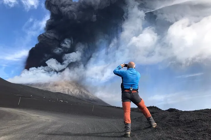 Guided hikers on the dark crater rim high on Mount Etna with the summit craters in view on a cable car and 4x4 summit excursion in Sicily