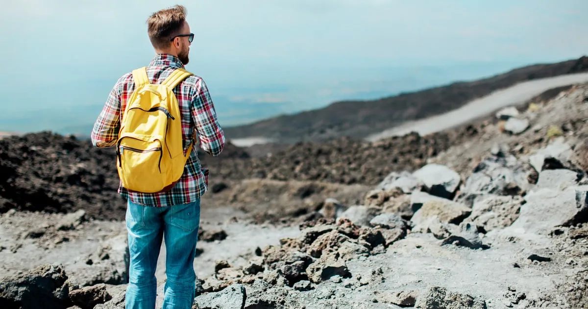 Travellers walking a trail between lava formations on Mount Etna during a half-day trek and lava cave tour from Catania, Sicily