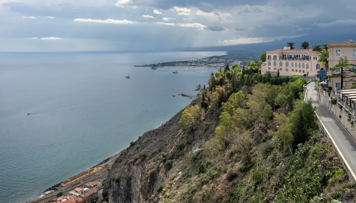 Taormina on the Ionian coast with Mount Etna tours departing from the town behind, Sicily